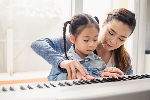 piano teacher and student sitting at a piano